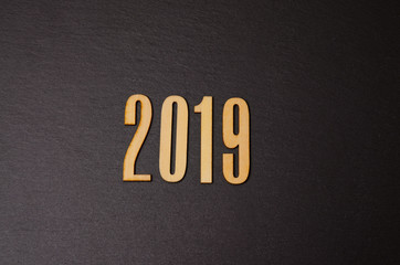 2019 on black background. Wooden sign 2019 on black. Design for a greeting card.