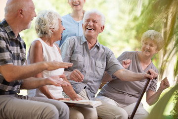 Smiling elderly woman and senior man during meeting with friends in the garden