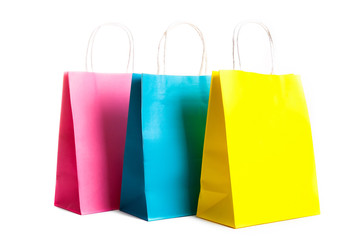 Many blank paper shopping bags of different colors, pink, blue and yellow isolated on white background. Blank colorful packets. Black friday sale concept. Close up copy space.