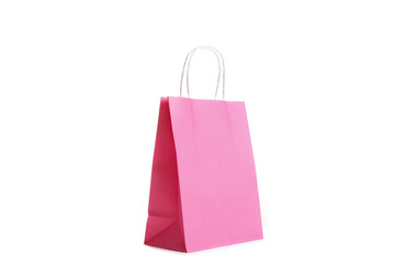 Single blank shoppong bag standing on isolated white background. Pink paper packet reflecting studio light. Black friday sale concept. Close up, copy space for text.