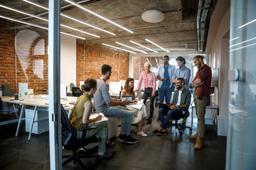 Group of businesswomen and businessmen having a meeting at modern open space office.