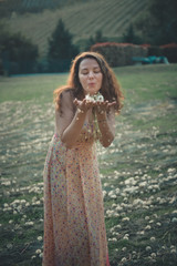 Fototapeta na wymiar happy beautiful woman blowing dandelion in the field