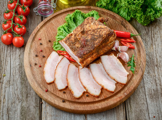 Slices of bacon on the wooden background.