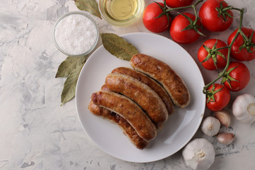 Grilled sausages with tomatoes, sunflower oil and garlic on a light background. top view
