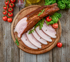 Slices of bacon on the wooden background.