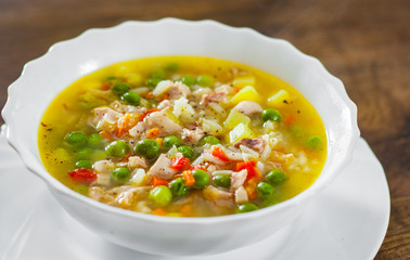 chicken soup with rice and vegetables in bowl on wooden table background