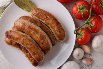 Grilled sausages with a variety of vegetables tomatoes and garlic on a light background. top view
