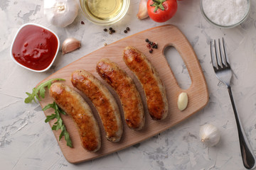 Grilled sausages with a variety of vegetables tomatoes and garlic, red sauce and spices on a light background. top view