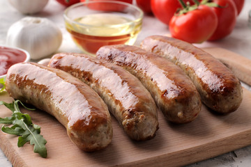 Grilled sausages with tomatoes, sunflower oil and garlic on a light background