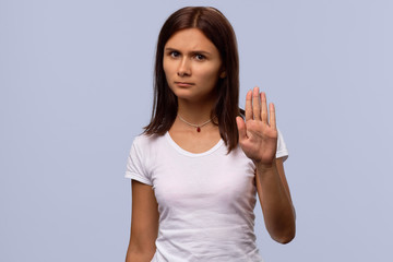 Brunette girl tries to prevent herself from something unpleasant isolated on blue background. A...