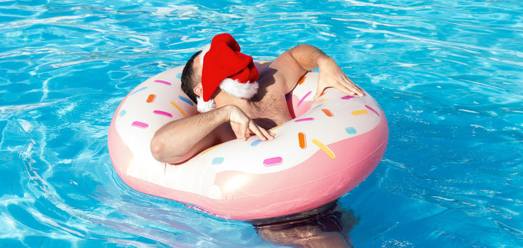 man in christmas hat walking in the swimming pool on sunny day ,feeling relax