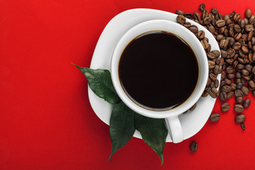 Coffee cup with coffee beans on red background.