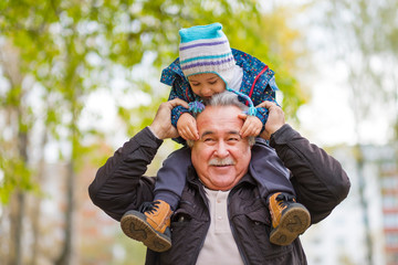 Shot of a happy senior man smiling looking away his grandson hugging him from behind copyspace...