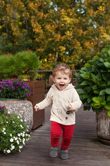 Little smiling boy runs on a terassa of cafe.  Lovely kid smiles and has joy. Outdoor activities for children