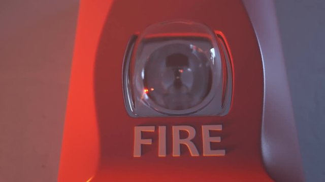 Close up shot of flashing strobe red fire alarm during fire in the room.