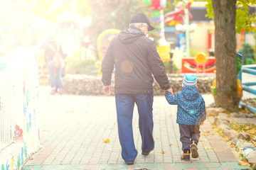 grandfather and grandson walk together in the park