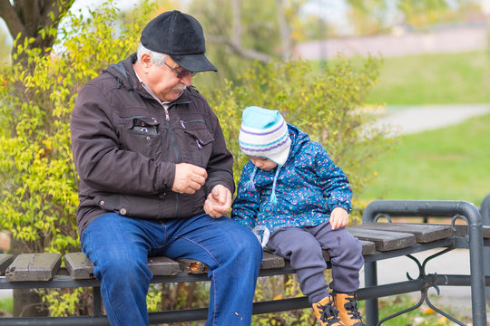 old grandfather and little grandson are sitting on a bench. concept of generations family. walk together