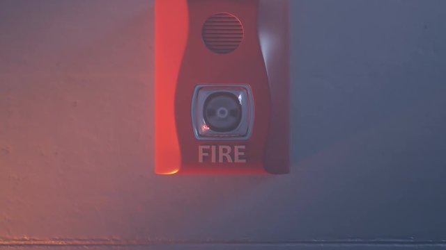 Close up shot of flashing strobe red fire alarm during fire in the room.