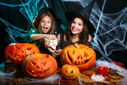 Happy Halloween. Beautiful caucasian mother with happy little daugther enjoy with Halloween candy and sweet over bats and spider web on black studio background.