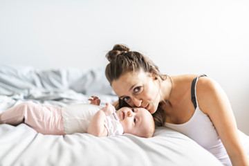 Portrait of a beautiful mother with her 2 month old baby in the bedroom