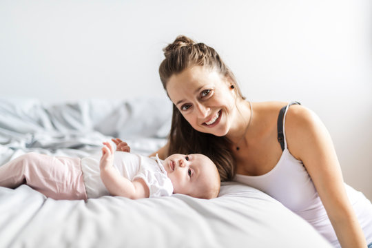 Portrait of a beautiful mother with her 2 month old baby in the bedroom