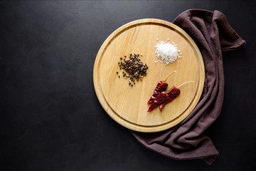 Round сatting board with ingredients for cooking and knife on dark wooden background. Top view. Copy space.