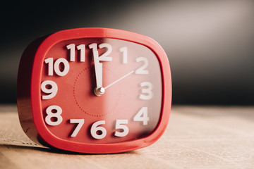 Red alarm clock on newspaper background with copy space, time passing concept for business deadline.
