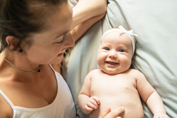 Portrait of a beautiful mother with her 2 month old baby in the bedroom