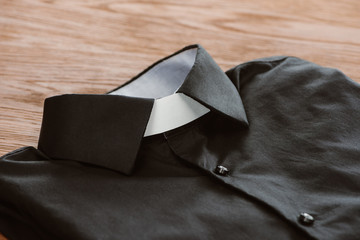 close-up shot of clerical shirt with white collar on wooden surface - obrazy, fototapety, plakaty