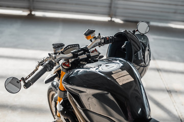 Close up of black glossy helmet at motorcycle handlebars. Urban background.