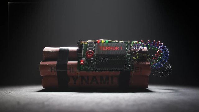 Armed TNT bomb isolated in dark room in spotlight. Terror word on a display.