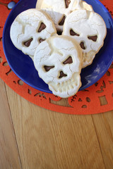 Halloween cookies filled with chocolate in shape of a skull on a plate on wooden table
