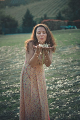 Fototapeta na wymiar Happy beautiful woman blowing dandelion in the field