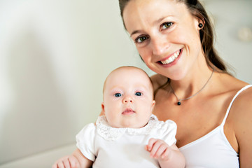 Portrait of a beautiful mother with her 2 month old baby in the bedroom