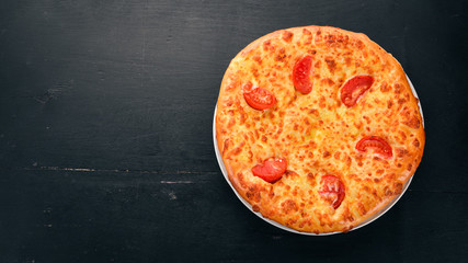 Khachapuri with tomatoes and cheese. Georgian cuisine. On the old wooden background. Free space for text. Top view.
