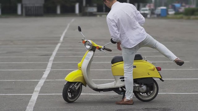 Guy goes to the scooter and starts the engine