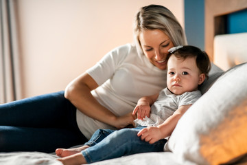 Mother Playing With Baby Daughter In Bedroom At Home