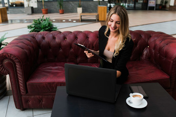 Obraz premium Beautiful smiling successful business woman sitting in the office and working on her laptop.