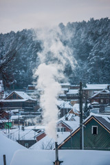 smoke comes out of the chimney. winter stove heating. frost in the village. smoke close up. snow covered roofs