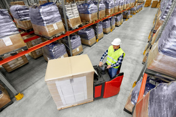 logistic business, shipment and people concept - loader operating forklift and loading boxes at warehouse