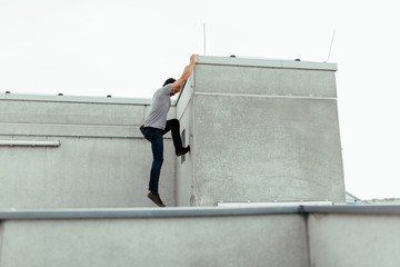 young man climbing the facade of building in the city