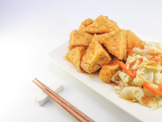 High angle view of fried stinky tofu with pickle vegetable, sauce. Chopsticks on the side isolated on white background. Snack at night market. Oriental,Asia,Taiwan food concept.With copy space.