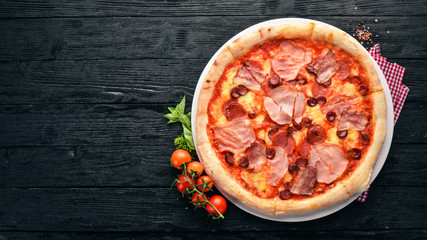 Pizza with bacon and sausages. Italian traditional dish. On the old background. Top view. Free space for your text.