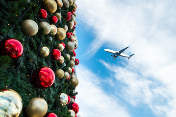 Naklejka premium Decorated Christmas tree and airplane in blue sky