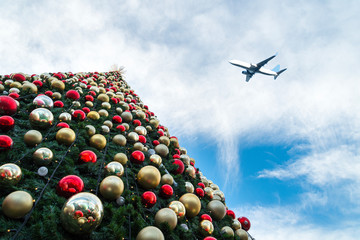 Obraz premium Decorated Christmas tree and airplane in blue sky