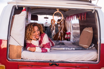 woman with curly hair and red and white striped warm sweater looks and smiles relaxed inside her...