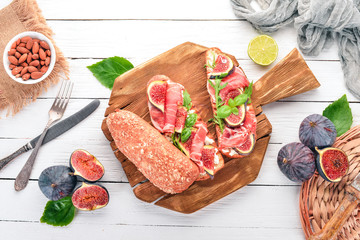 Bruschetta with prosciutto, fresh figs and cheese. On the old background. Healthy food. Free space for text. Top view.