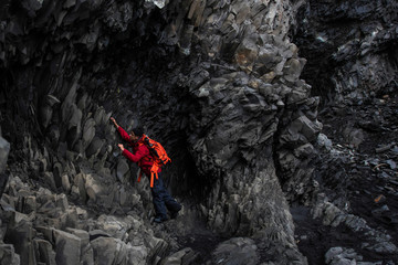 Male tourists are climbing lava rock at Black Sand in Iceland.