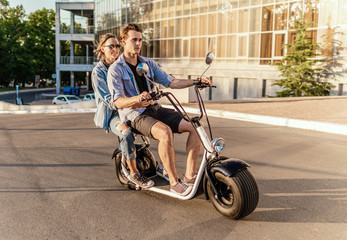 Plakat Lovely young couple driving electric bike. Modern city transportation
