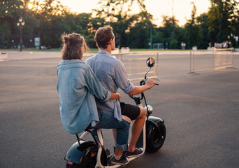 Lovely young couple driving electric bike during summer. Modern city dating and transportation